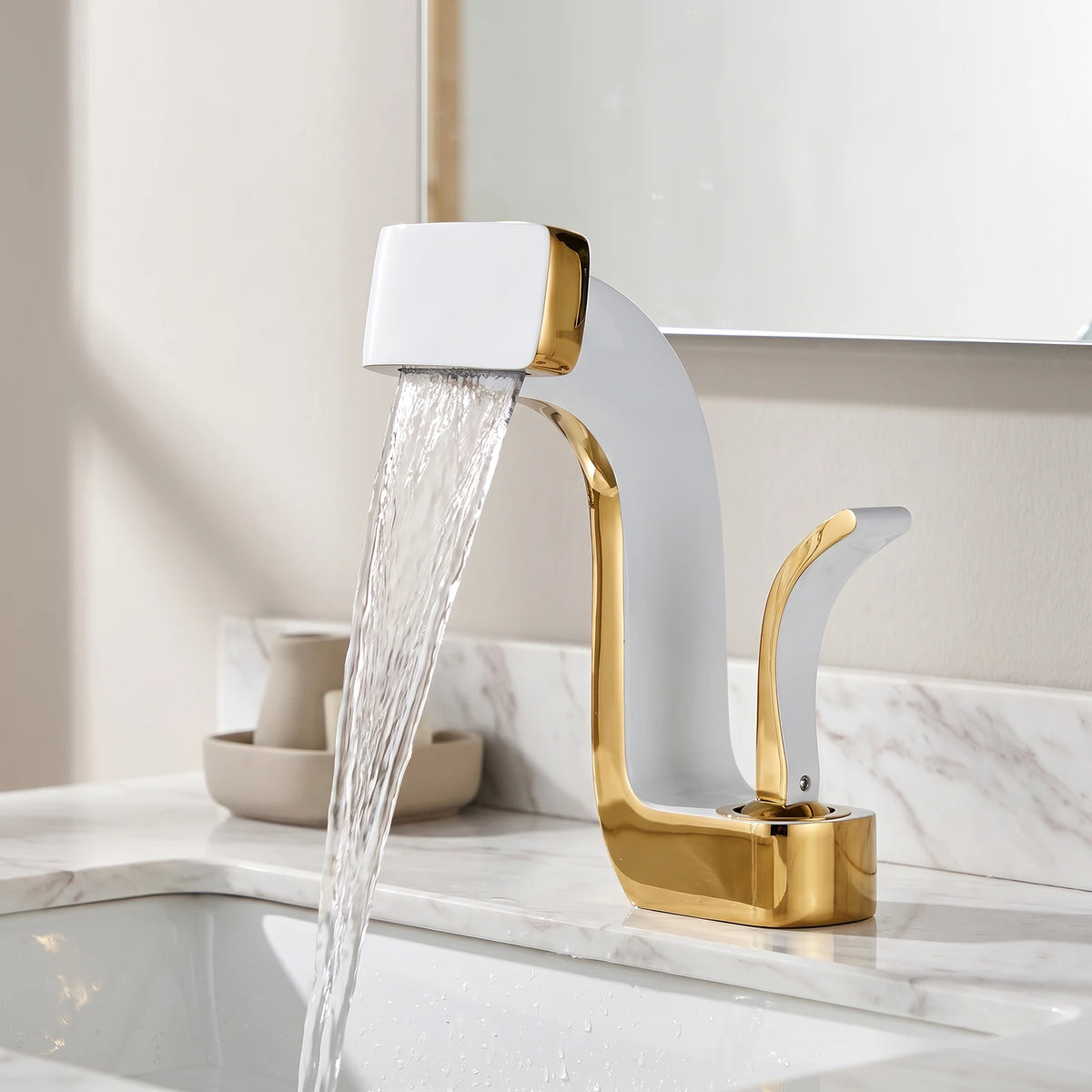 Torneira Louise Branco com Dourado instalada em bancada de mármore branco, com água em cascata caindo na cuba