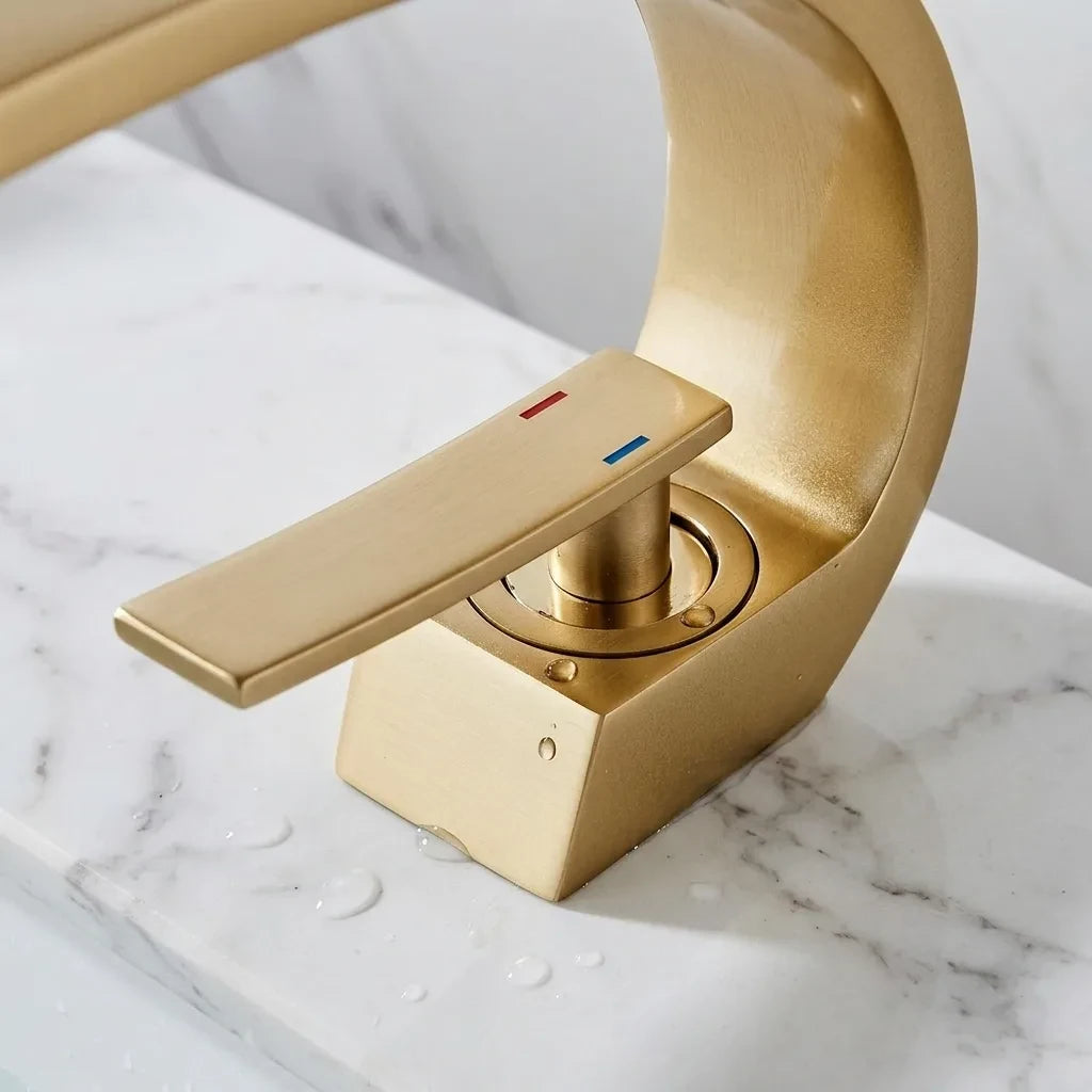 Torneira para banheiro monocomando luxury dourada escovada quente e fria, detalhe da base instalada na bancada — Toque de Casa