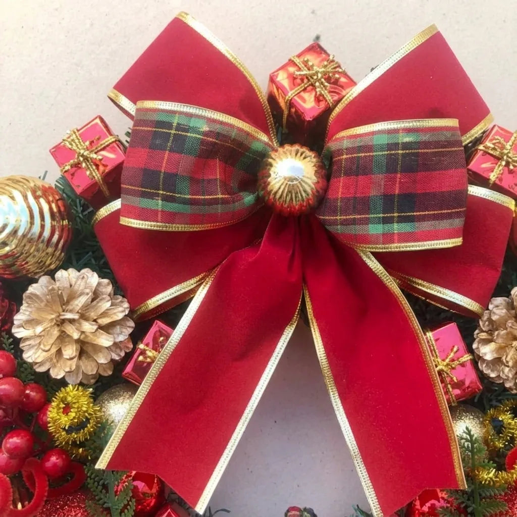 Detalhe do laço vermelho xadrez com contorno dourado, pequenos presentes e pinhas da guirlanda natalina