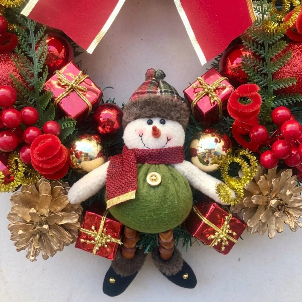 Detalhe do boneco de neve com barriga verde, cachecol vermelho, pinhas douradas e presentes da guirlanda