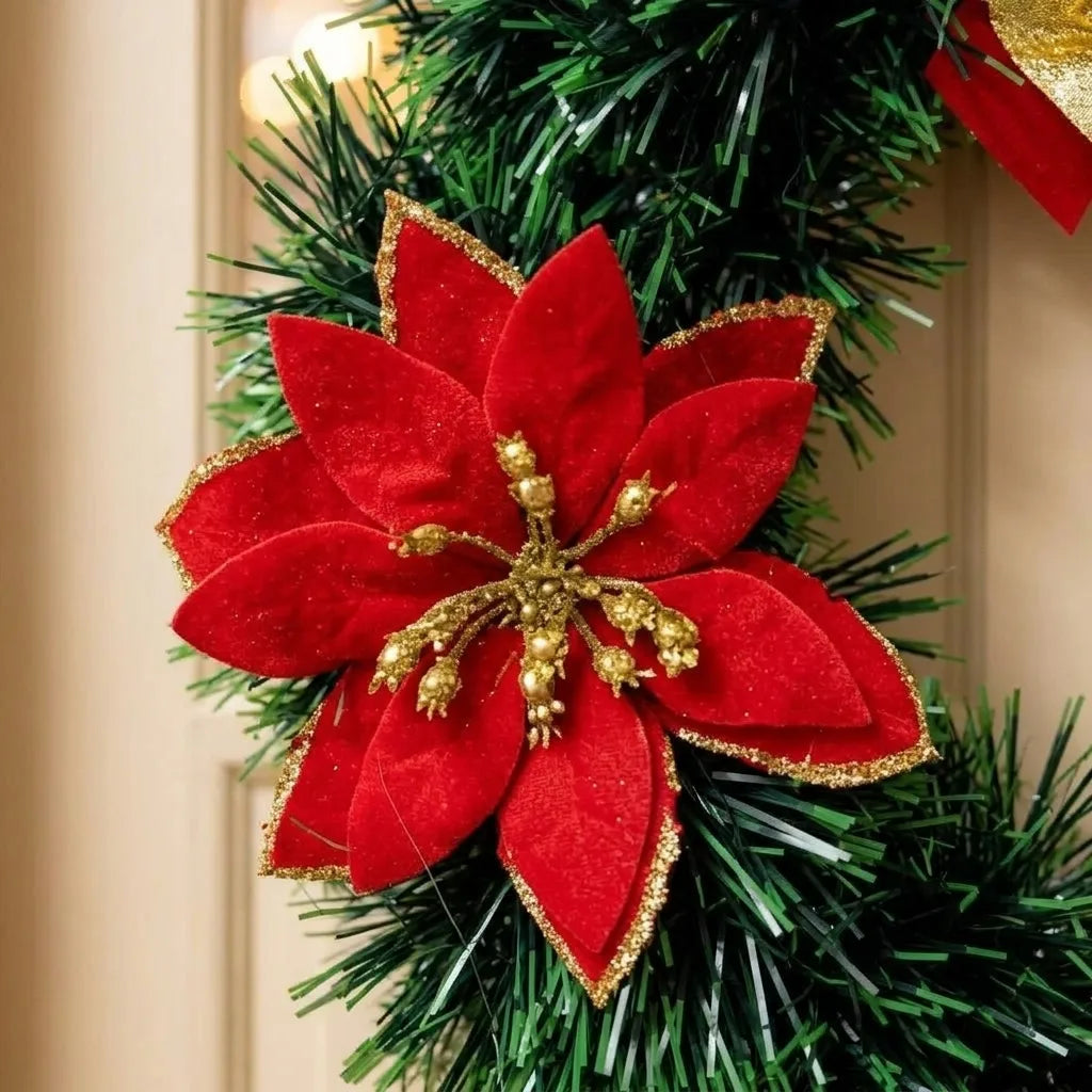 Detalhe da flor vermelha com centro dourado e folhagem da guirlanda natalina de 25 cm.