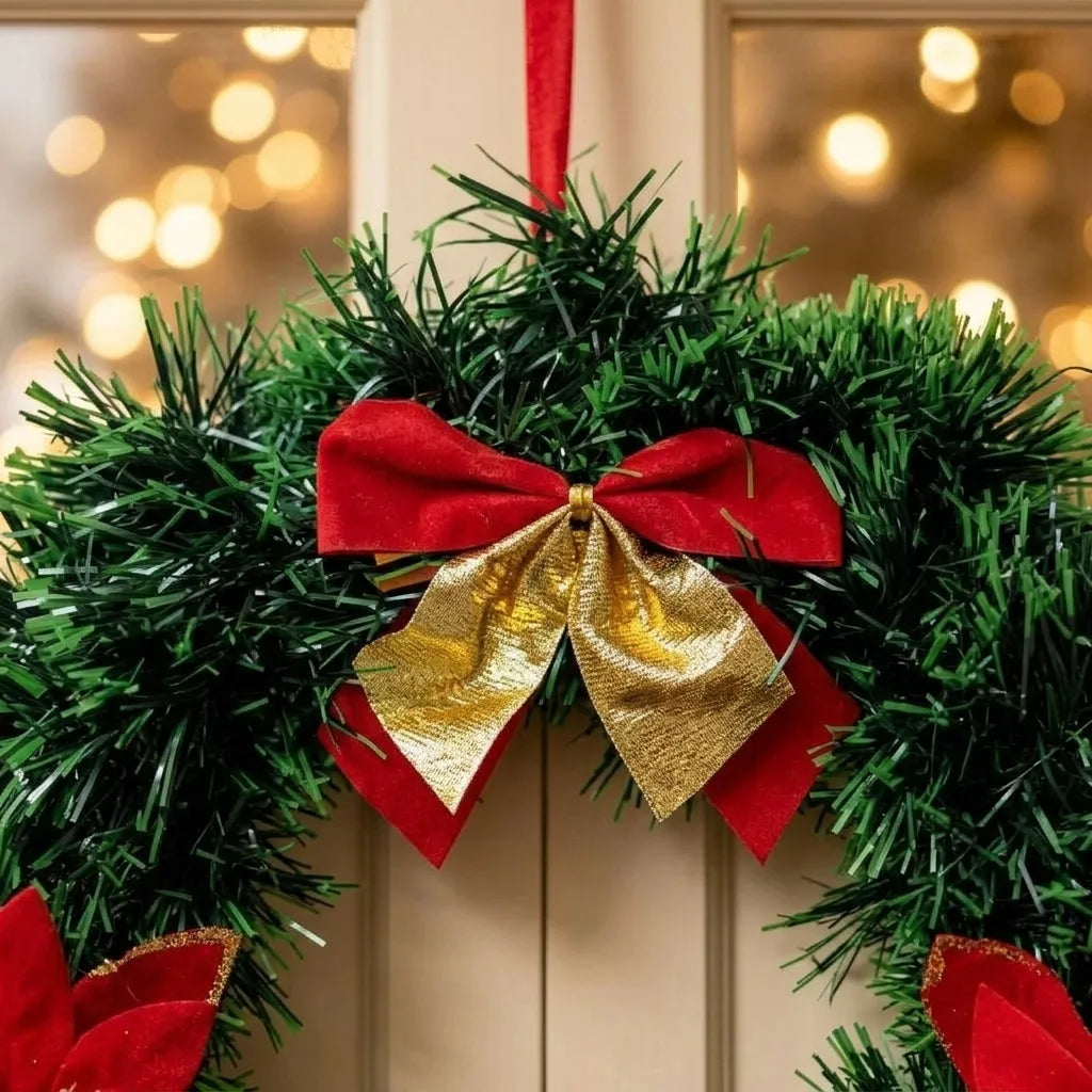 Detalhe do laço vermelho e dourado sobre a folhagem da guirlanda de Natal de 25 cm.