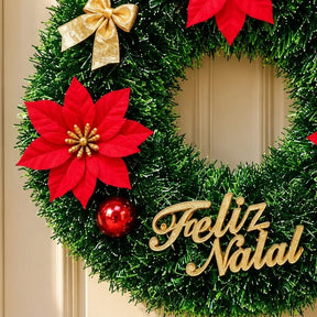 Detalhe do laço dourado e placa Feliz Natal em um exemplo da guirlanda sortida de 40 cm; envio de 1 modelo aleatório.