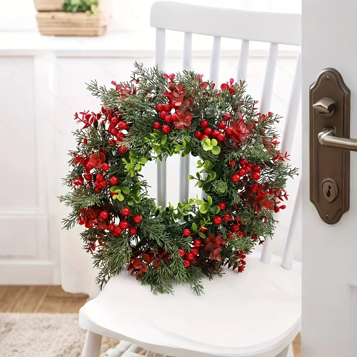 Guirlanda de Natal de 35 cm com folhagem e frutos vermelhos apoiada em cadeira branca