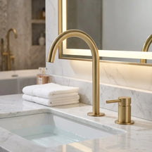 Torneira Salerno para banheiro ouro escovado, instalada em bancada de mármore branco com espelho de LED — Toque de Casa
