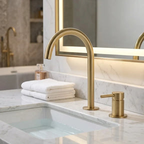 Torneira Salerno para banheiro ouro escovado, instalada em bancada de mármore branco com espelho de LED — Toque de Casa