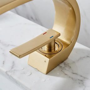 Torneira para banheiro monocomando luxury dourada escovada quente e fria, detalhe da base instalada na bancada — Toque de Casa